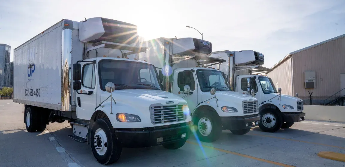 A line of IM UP Trucking commercial semi-trucks parked in front of a facility